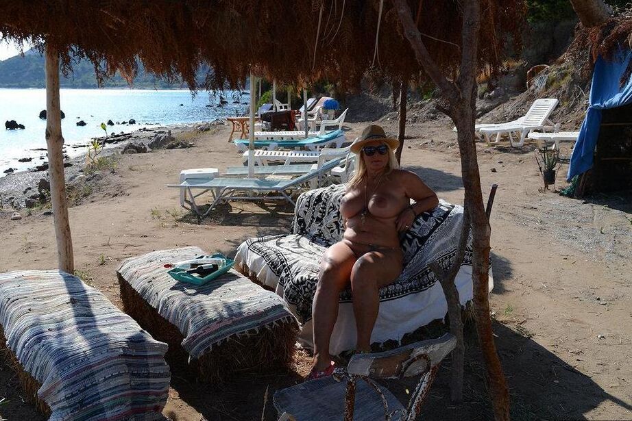 18P Dicke blonde Frau mit großen Brüsten wandert mit Strohhut an einem FKK-Strand entlang
