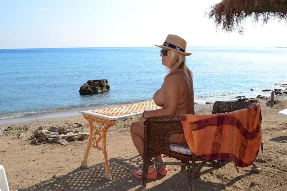 18P Dicke blonde Frau mit großen Brüsten wandert mit Strohhut an einem FKK-Strand entlang