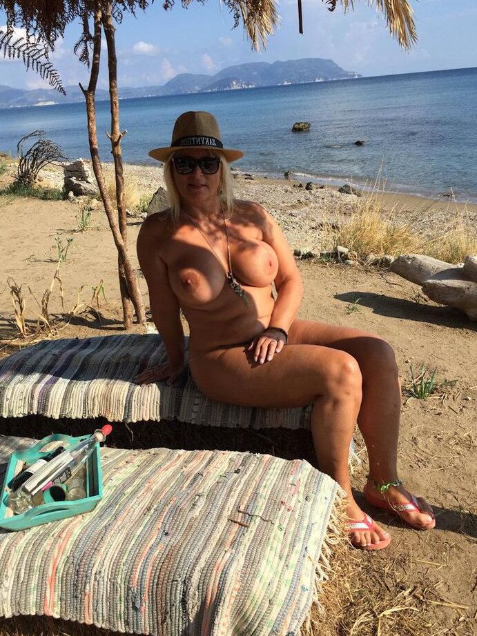 18P Dicke blonde Frau mit großen Brüsten wandert mit Strohhut an einem FKK-Strand entlang
