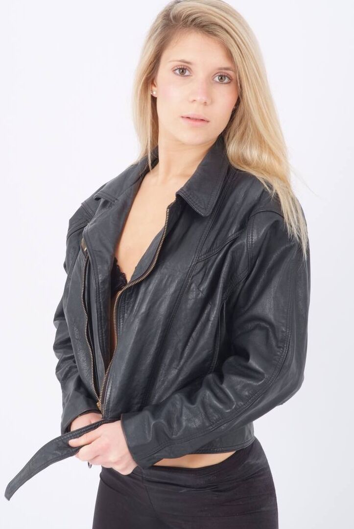 15P Blond chick unzips her leather jacket in a black bra and leggings