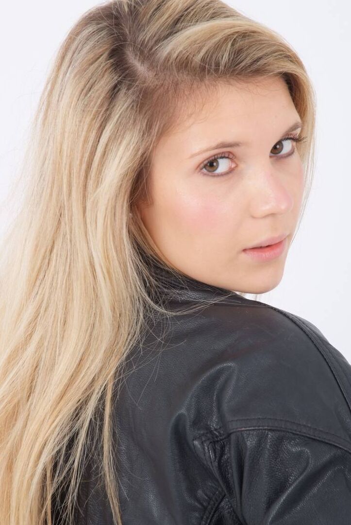 15P Blond chick unzips her leather jacket in a black bra and leggings
