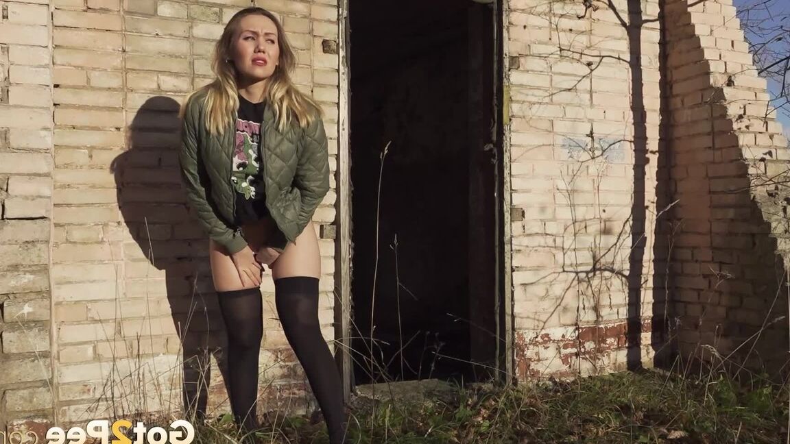 15P Une femme de race blanche remonte sa jupe avant de pisser près d'un immeuble en brique