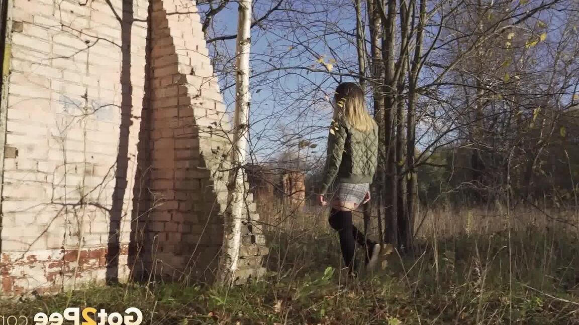 15P Une femme de race blanche remonte sa jupe avant de pisser près d'un immeuble en brique