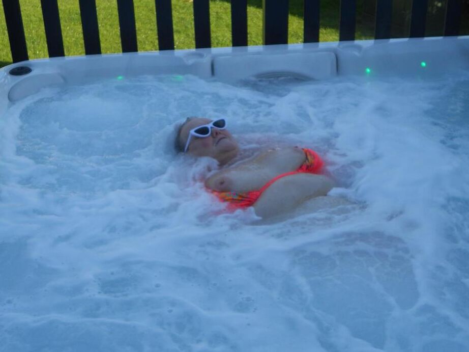 20P Fat nan bares her boobs while in a patio hot tub before getting naked on a bed
