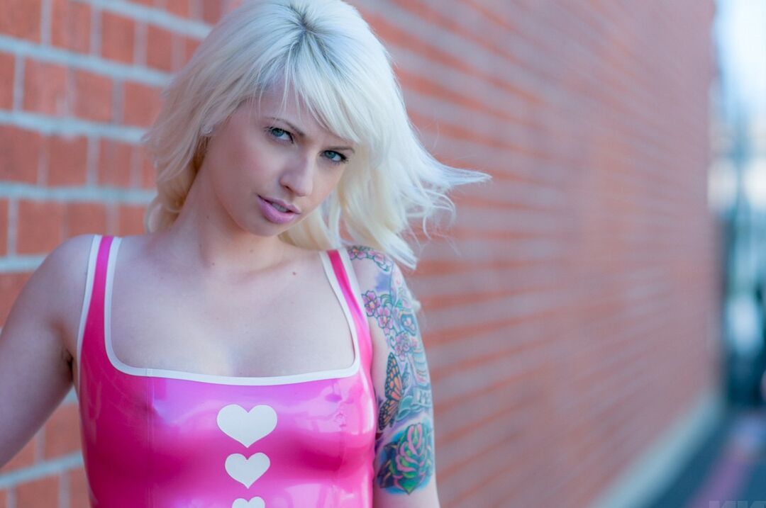 15P A modelo amadora Lynn Pops desfila no estacionamento usando um vestido rosa de látex