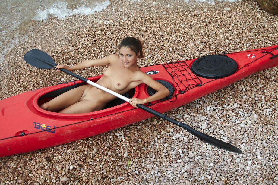 16P Das nackte Babe Sati posiert im Kajak am wilden Strand