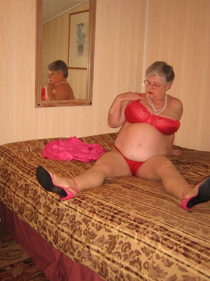 20P Silver haired nan Girdle Goddess pulls her hose down around her knees on a bed
