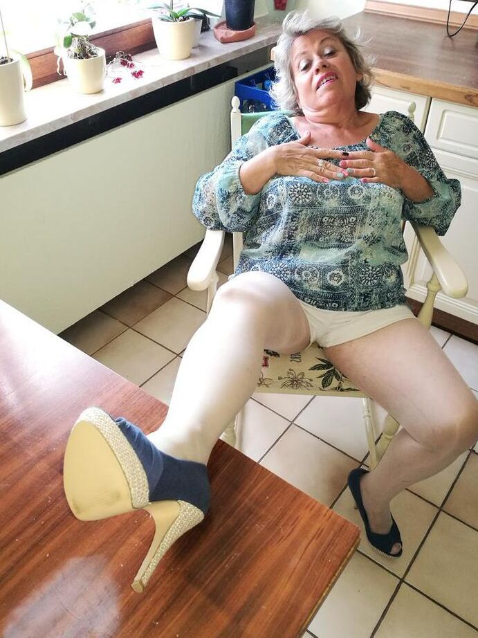 20P Old woman Caro pulls down her pantyhose in high heels at kitchen table