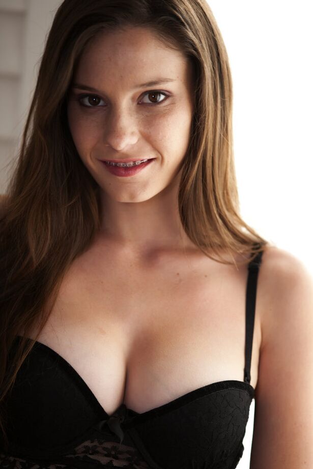 18P Chica de buenas tetas Rilee Marks vestida con lencería de encaje negro inclinándose para mostrar el culo