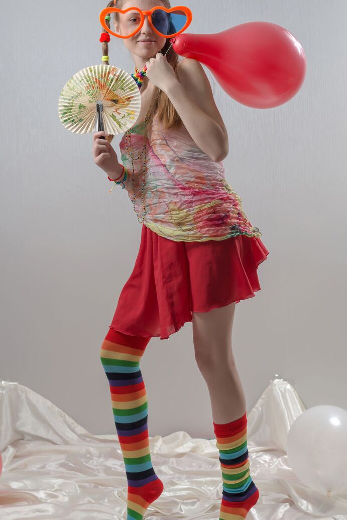 20P Uma adolescente magrinha com tranças e meias multicoloridas tira a roupa