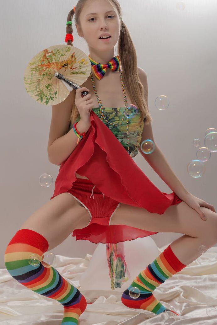 20P Uma adolescente magrinha com tranças e meias multicoloridas tira a roupa