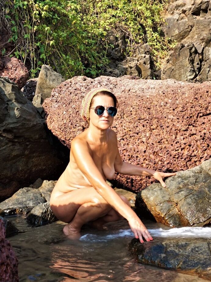 15P Older lady Diana Ananta models naked in sunglasses as the tide rushes in