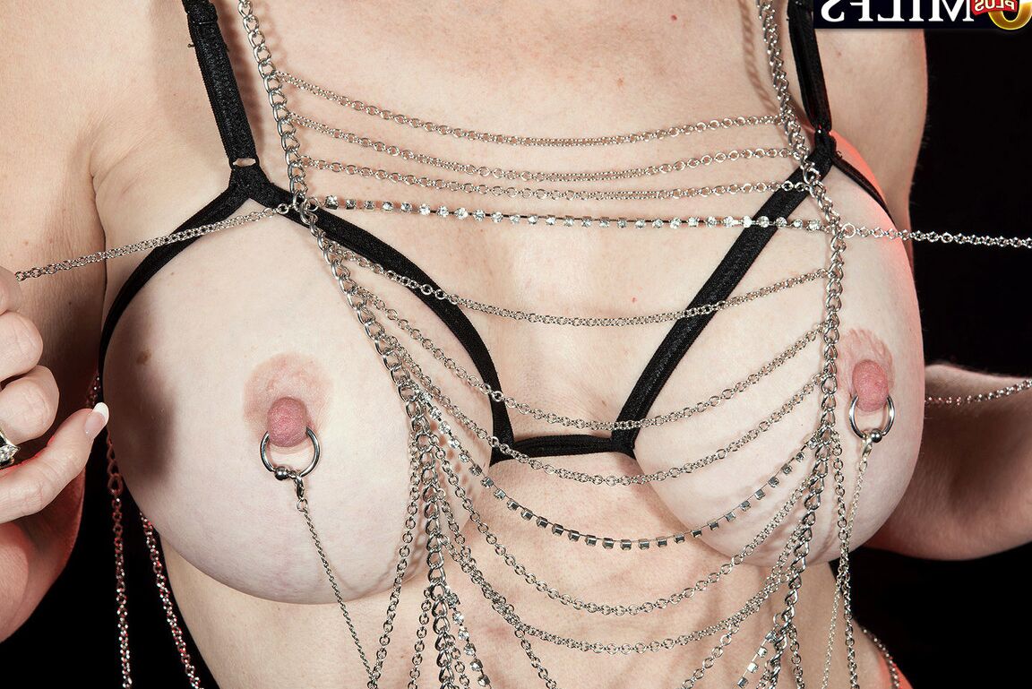 16P Mature lady Cammille Austin shows off her pierced nipples in chains and thong