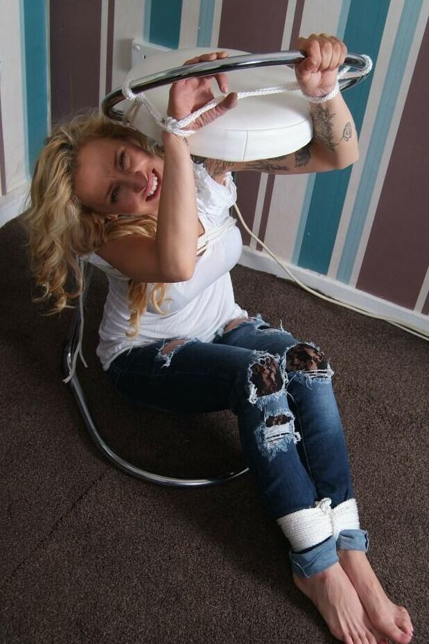 16P Fully clothed blonde Katie C struggles while restrained with rope bindings