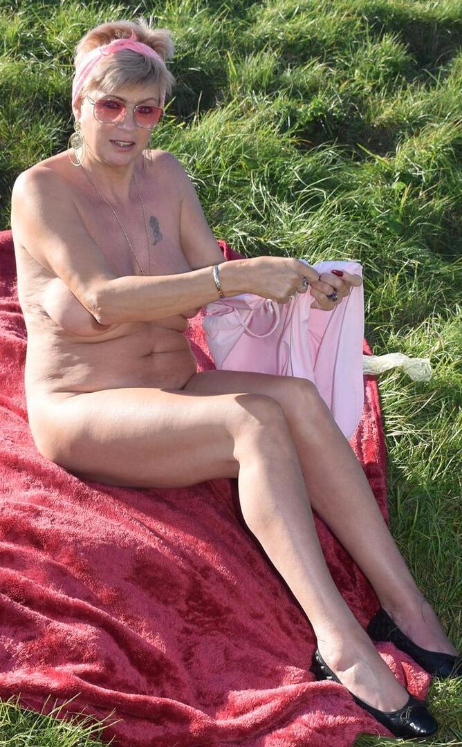 16P Older blonde Dimonty shows her natural tits while getting dressed in a field