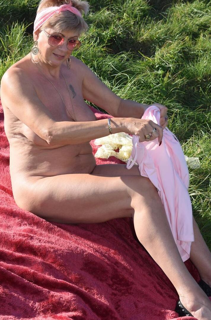 16P Older blonde Dimonty shows her natural tits while getting dressed in a field