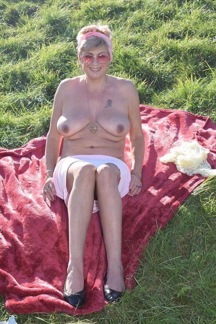 16P Older blonde Dimonty shows her natural tits while getting dressed in a field