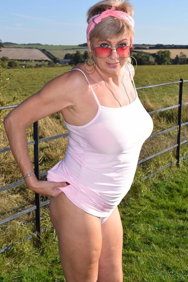 16P Older blonde Dimonty shows her natural tits while getting dressed in a field