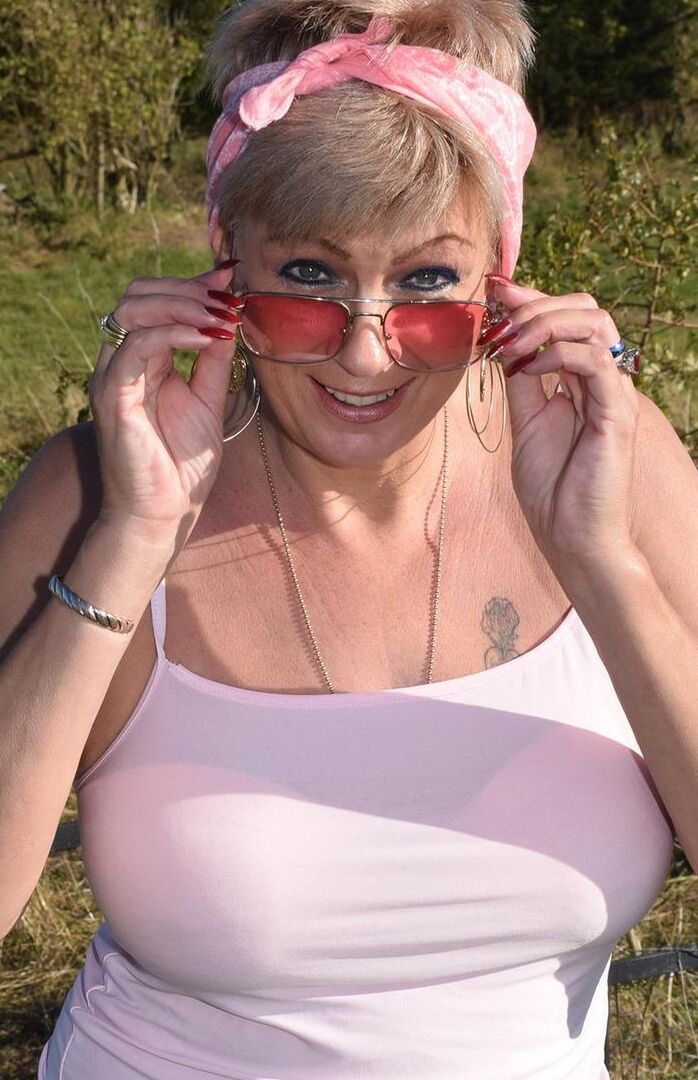 16P Older blonde Dimonty shows her natural tits while getting dressed in a field