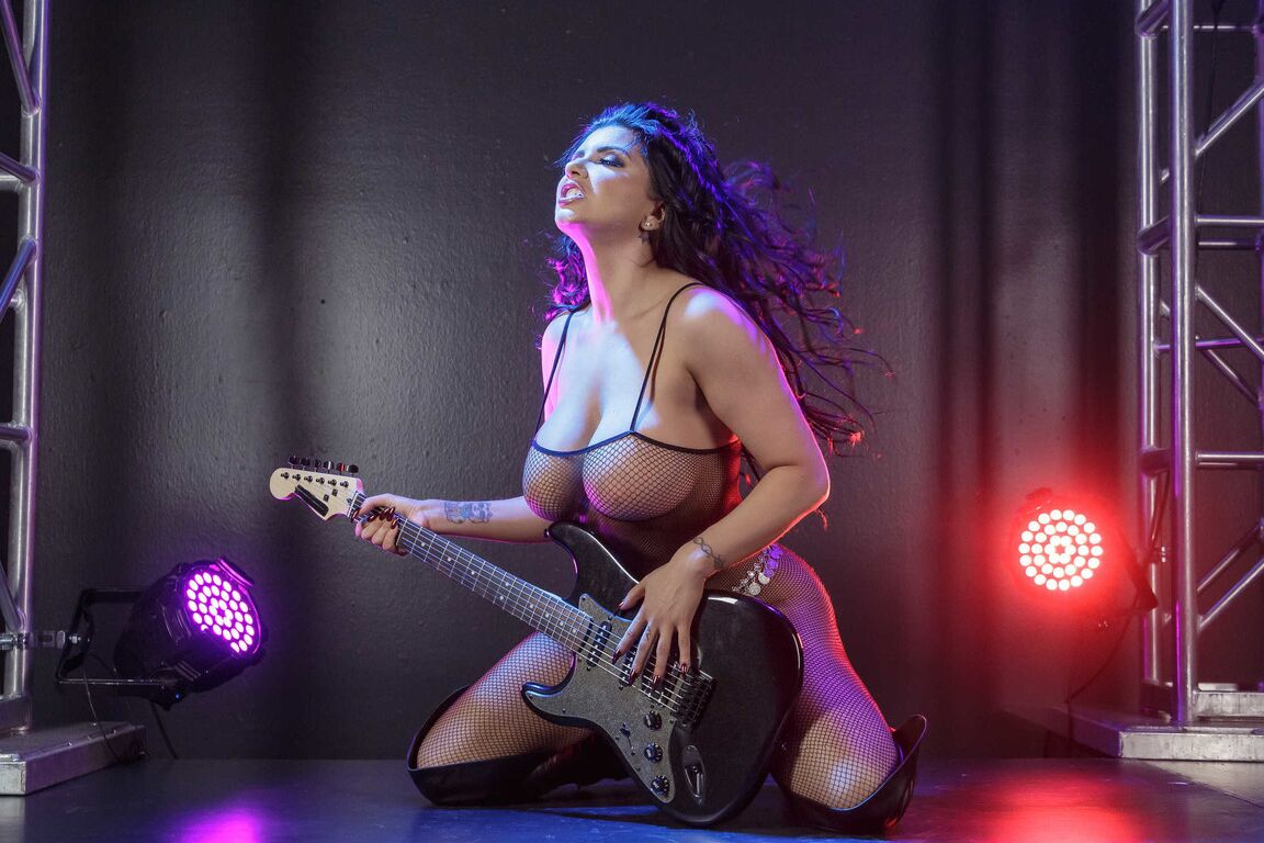 21P Busty MILF rock star Romi Rain strips on the stage & plays in fishnets & boots