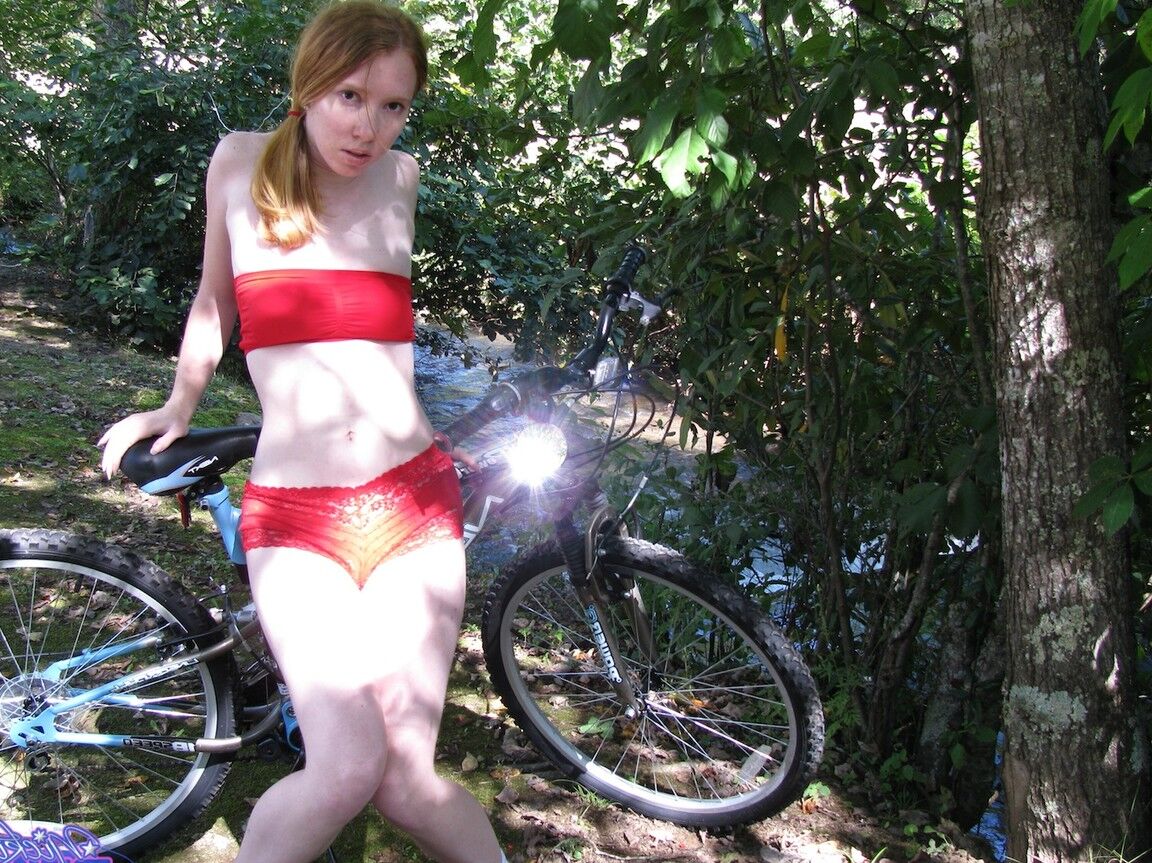 15P Young redhead Nicki Blue somewhat pulls down her shorts on top of her bicycle