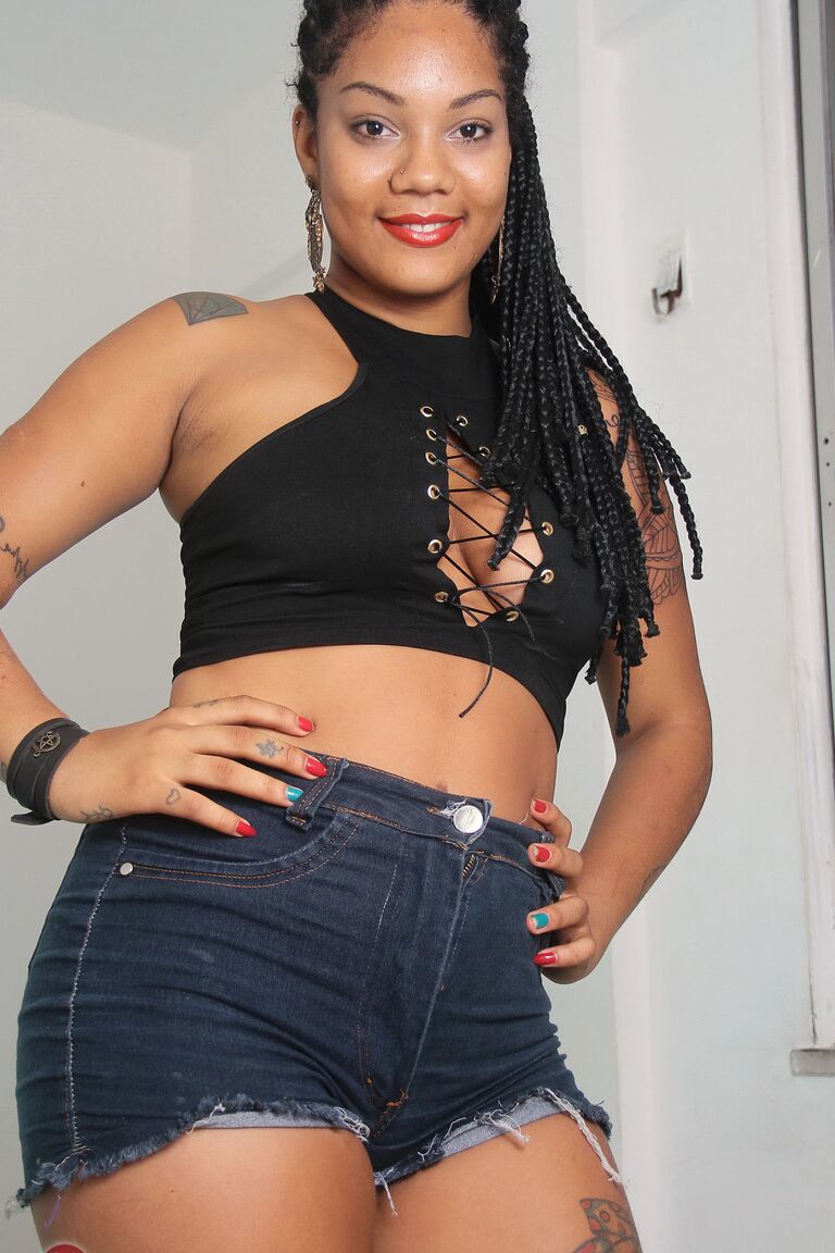 21P Carina de ébano exótico revelando seu corpo curvilíneo tatuado em um solo