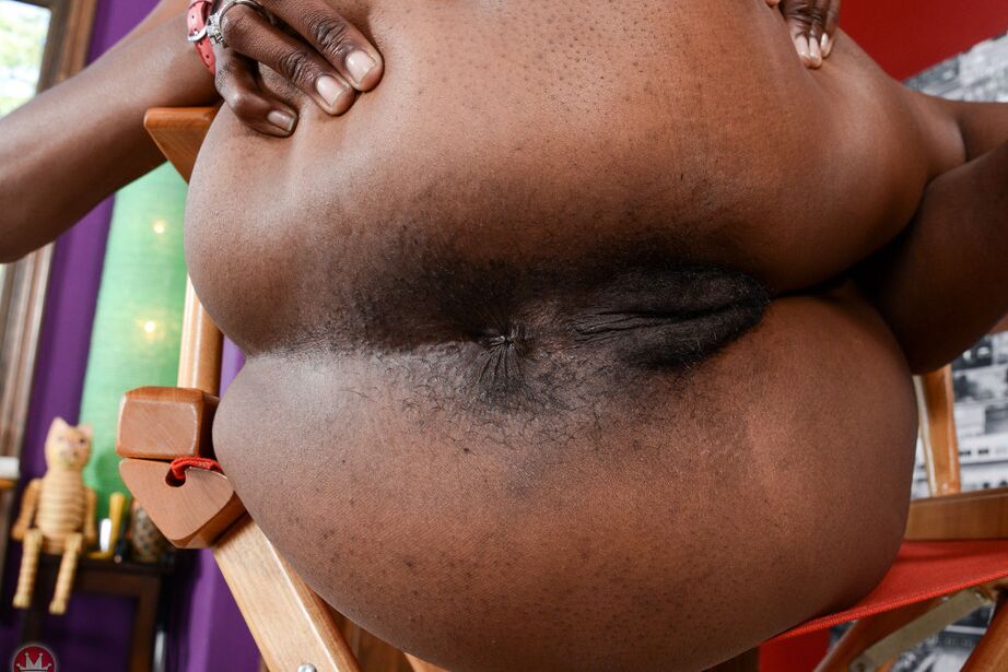 Die 16P-schwarze Debütantin Ebony Desire spreizt ihren gestutzten Busch auf einem Regiestuhl