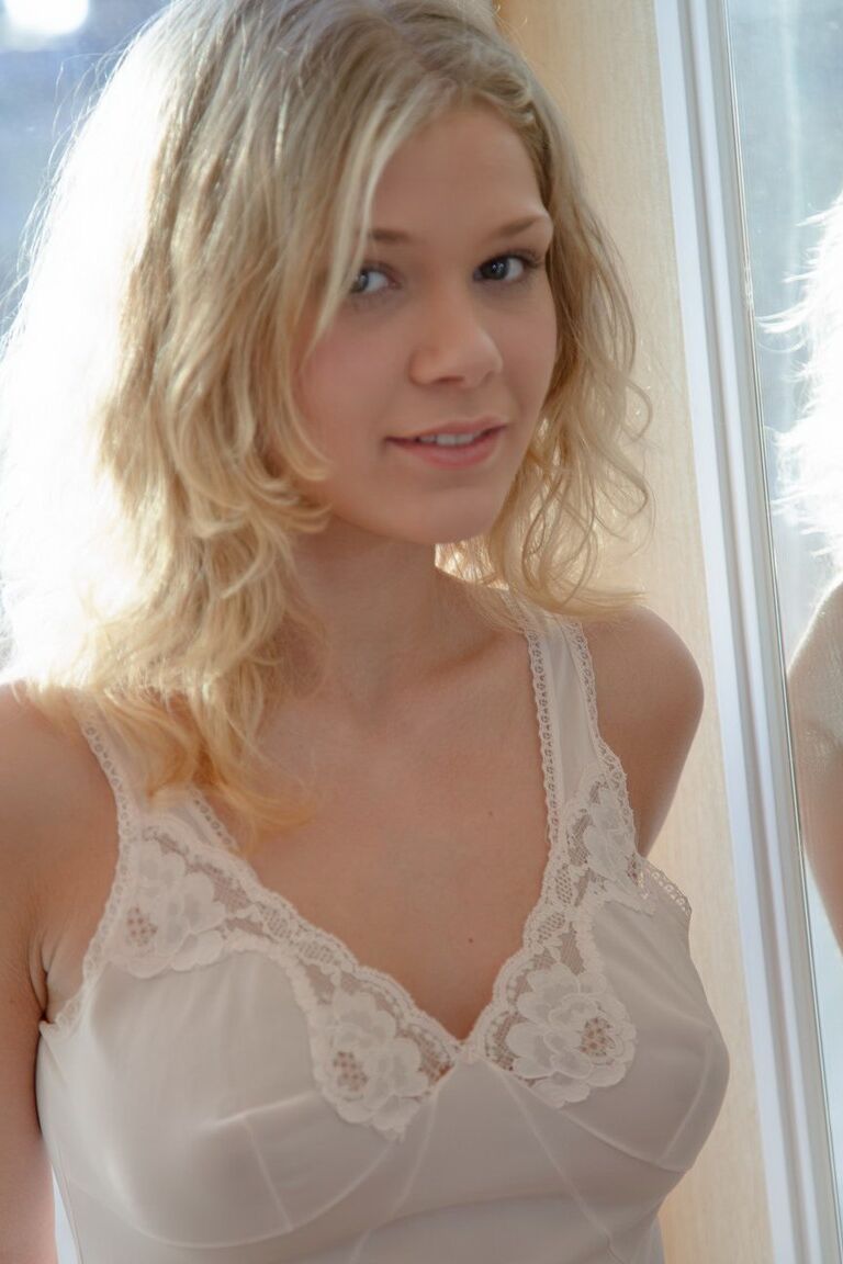 15P Sexy blonde Teenagerin Valya zieht weiße Dessous vor einem Fenster aus
