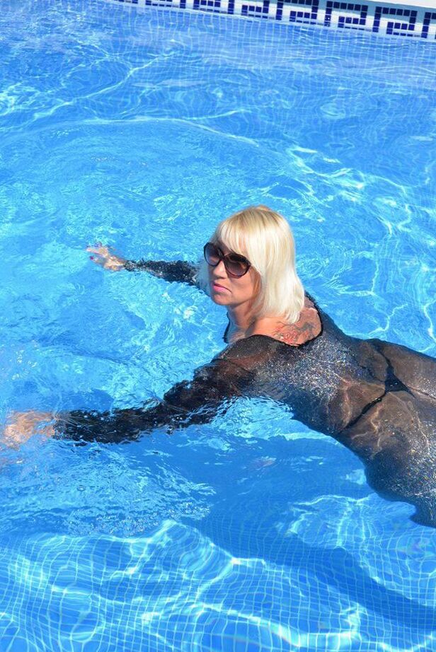 Die 20-jährige Amateurin Melody zieht vor dem Schwimmen in einem Body und einer Sonnenbrille ihre Absätze aus