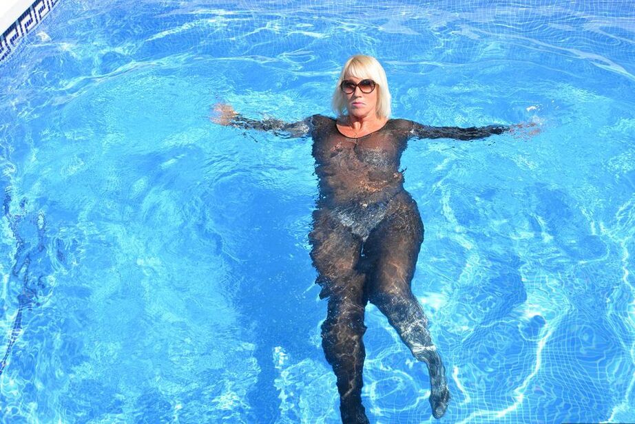 Die 20-jährige Amateurin Melody zieht vor dem Schwimmen in einem Body und einer Sonnenbrille ihre Absätze aus