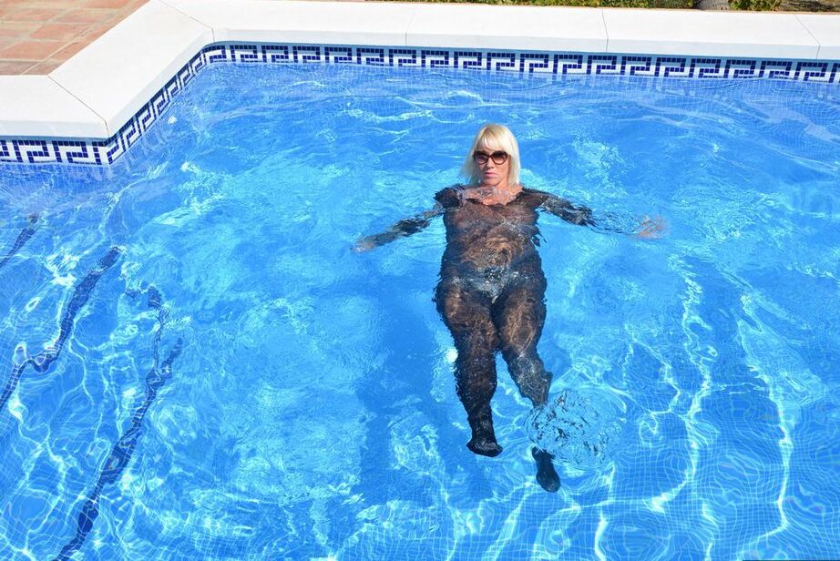 Die 20-jährige Amateurin Melody zieht vor dem Schwimmen in einem Body und einer Sonnenbrille ihre Absätze aus