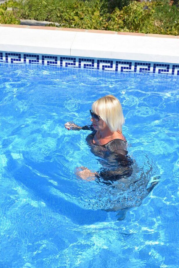 Die 20-jährige Amateurin Melody zieht vor dem Schwimmen in einem Body und einer Sonnenbrille ihre Absätze aus