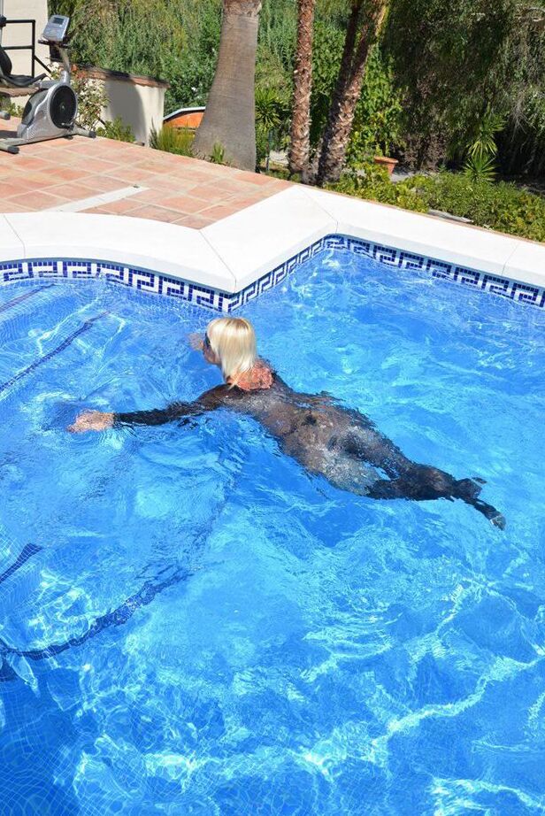 Die 20-jährige Amateurin Melody zieht vor dem Schwimmen in einem Body und einer Sonnenbrille ihre Absätze aus