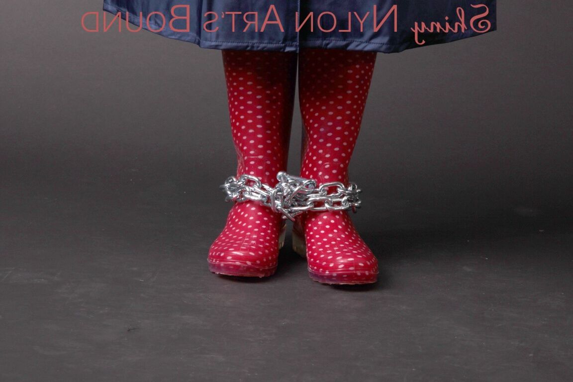 16P Mara wearing a rain skirt and a rain coat with rubber boots being tied and