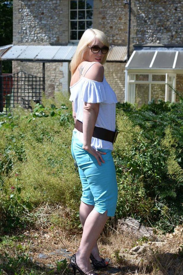 20P Middle-aged blonde Melody models in a bra while in a backyard