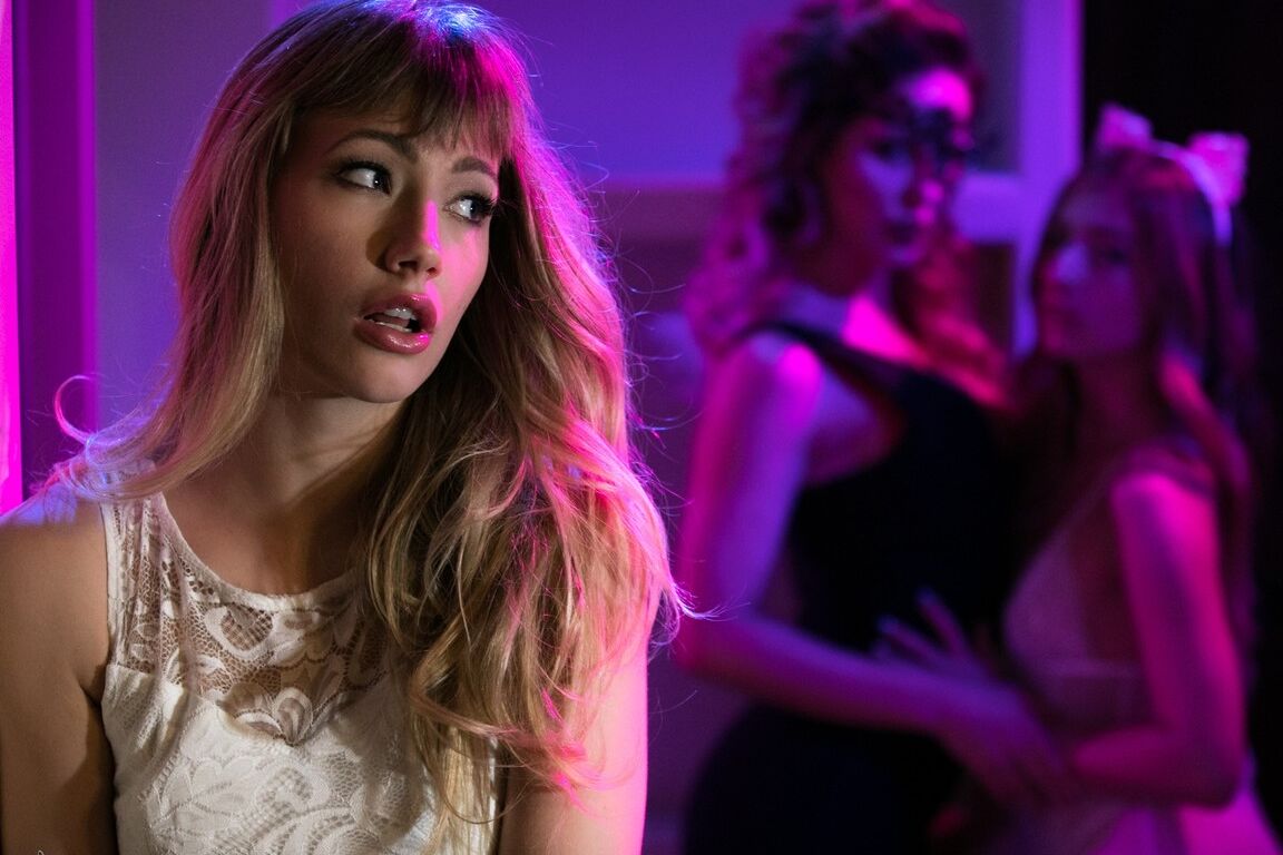 15P Ivy Wolfe stands uncomfortably at a party, wearing a masquerade mask Musing