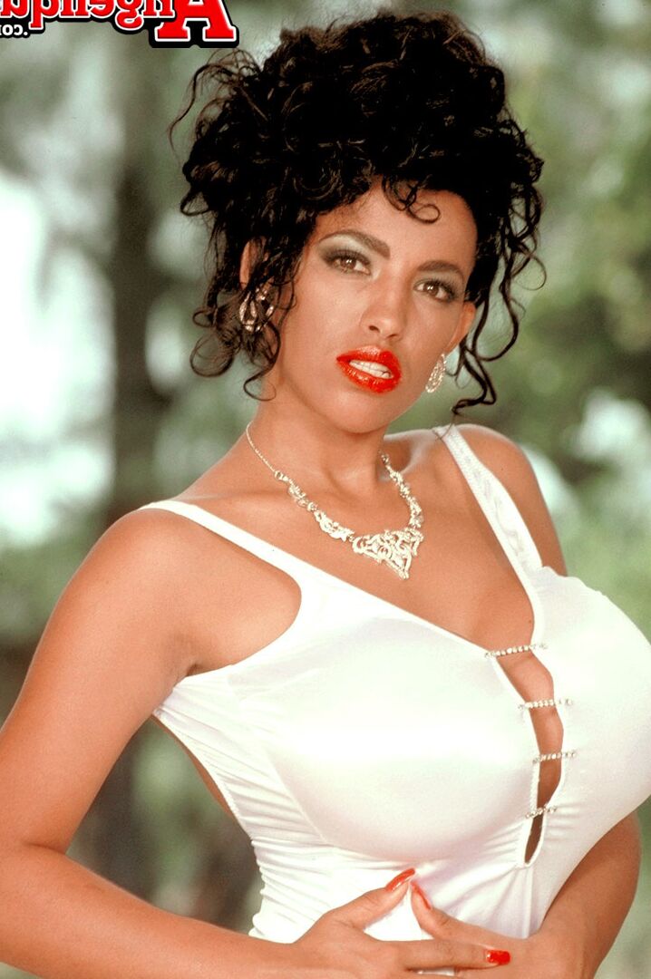 16P La mujer latina mayor Angelique luce labios rojos mientras muestra sus pechos postizos