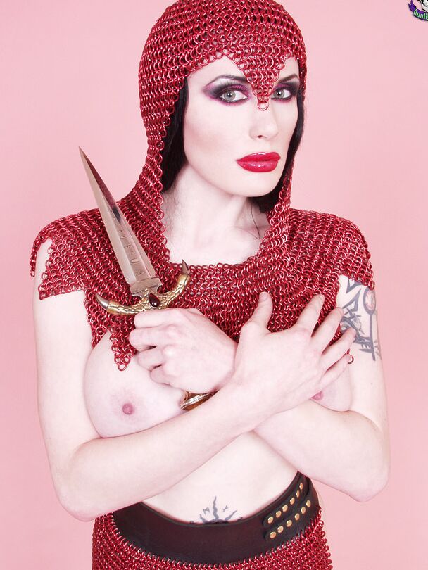 15P Busty chick Morrigan Hel licks a dagger while wearing chain mail and OTK boots