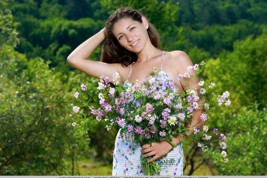 18P グラマーモデルのローゼラが池のそばでヌードポーズをとる前に野の花を抱く