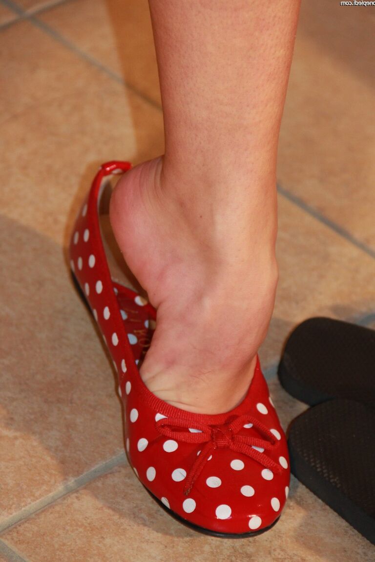 10P Une femme vêtue avec des ongles peints glisse ses pieds flexibles dans des chaussures plates
