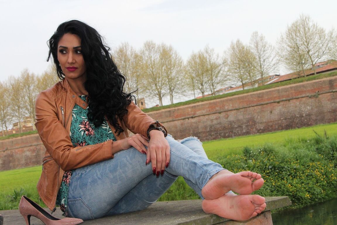 12P Dark-haired female Mistress Alexya displays her bare feet in a public setting