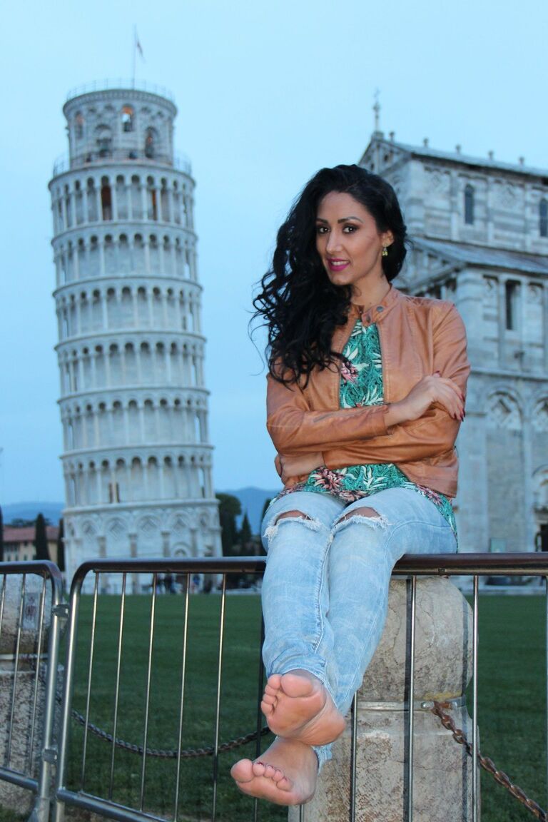 12P Dark-haired female Mistress Alexya displays her bare feet in a public setting