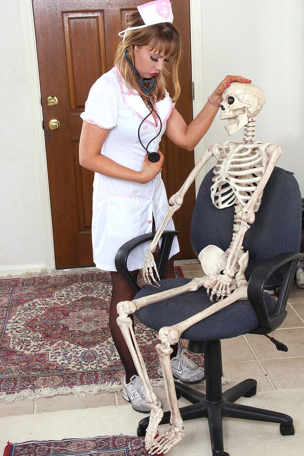 15P Die sexy Krankenschwester Christy James zieht ihre weiße Uniform aus, um sich auf ein Skelett zu setzen