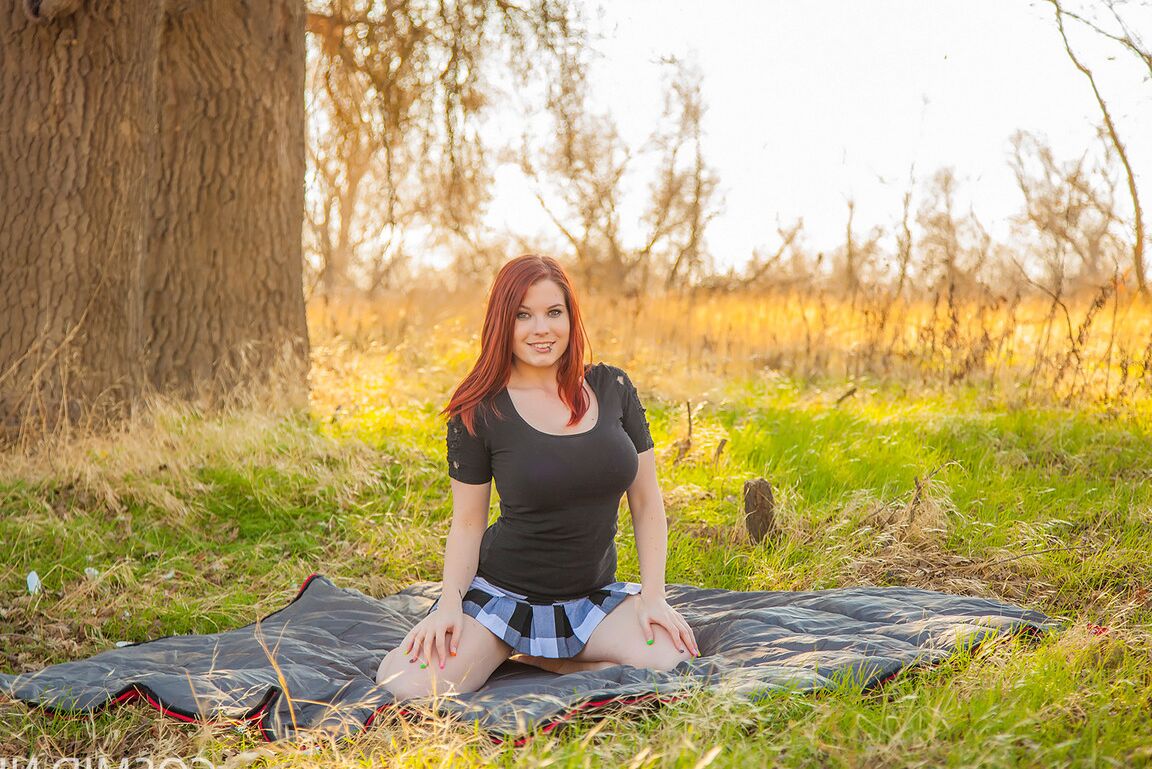 16P Raven, rousse et plantureuse, se met à genoux avec des seins nus pour montrer une jupe haute nue