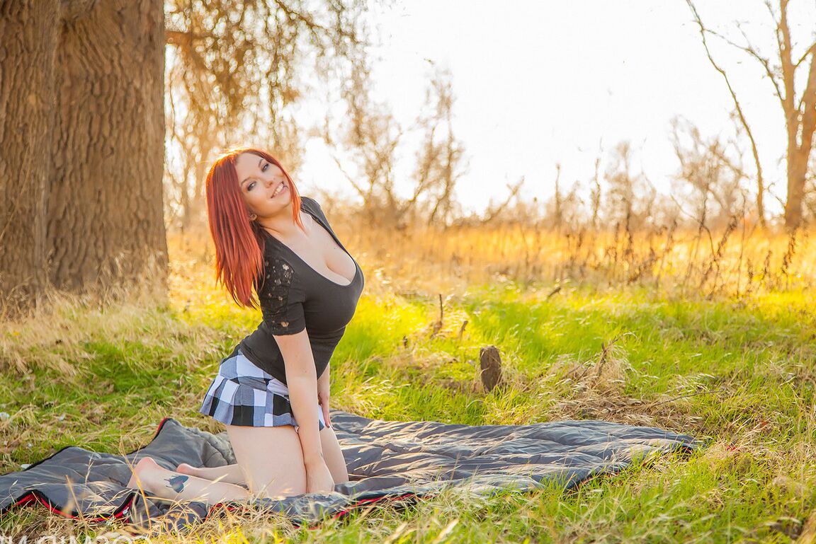 16P Raven, rousse et plantureuse, se met à genoux avec des seins nus pour montrer une jupe haute nue