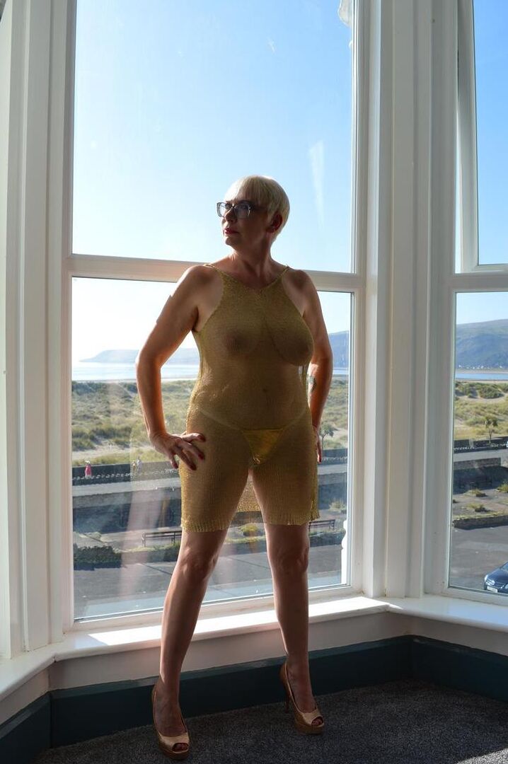 16P Big titted older woman Barby Slut showcases her bald twat in front of a window