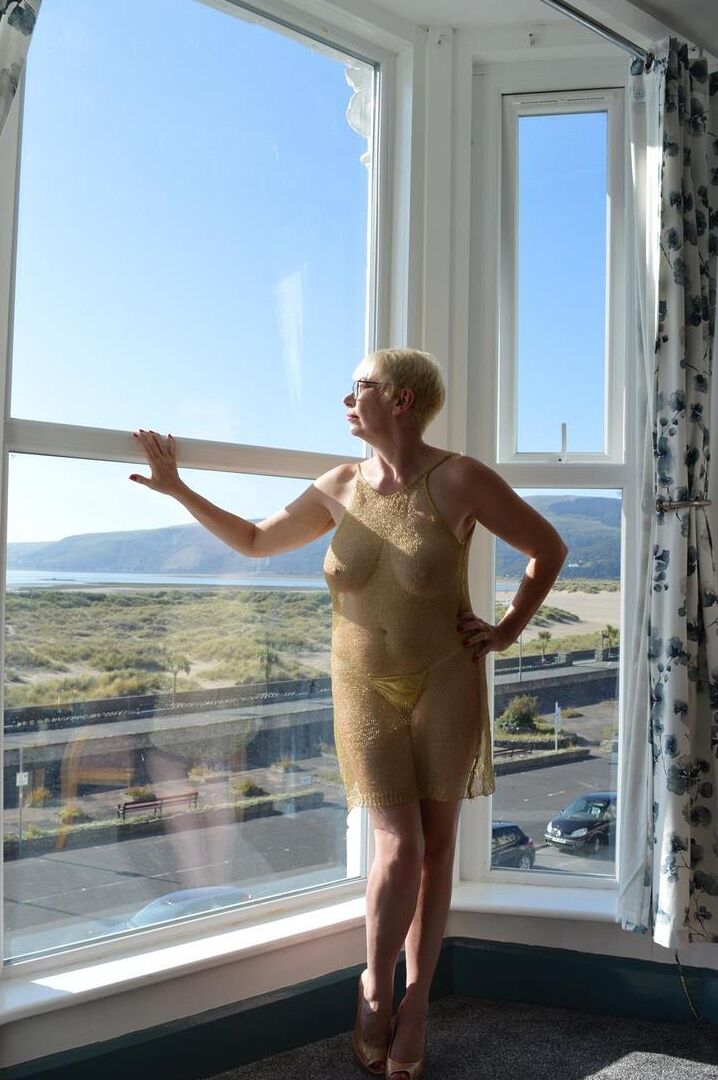 16P Big titted older woman Barby Slut showcases her bald twat in front of a window