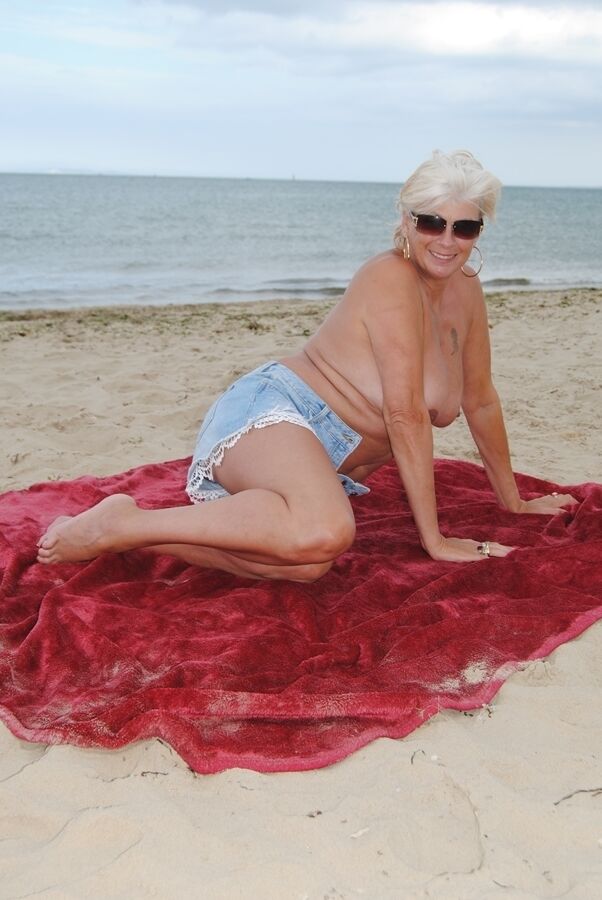 20P La blonde mature Dimonty mange une friandise glacée après avoir posé nue sur une plage