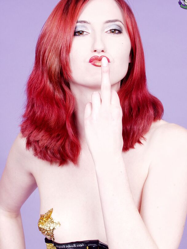 15P Pale redhead Kendra James models naked before adorning a corset and heels