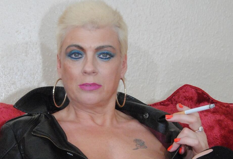 18P A loira Dimonty, com mais de 30 anos, tira um casaco de couro enquanto fuma um cigarro